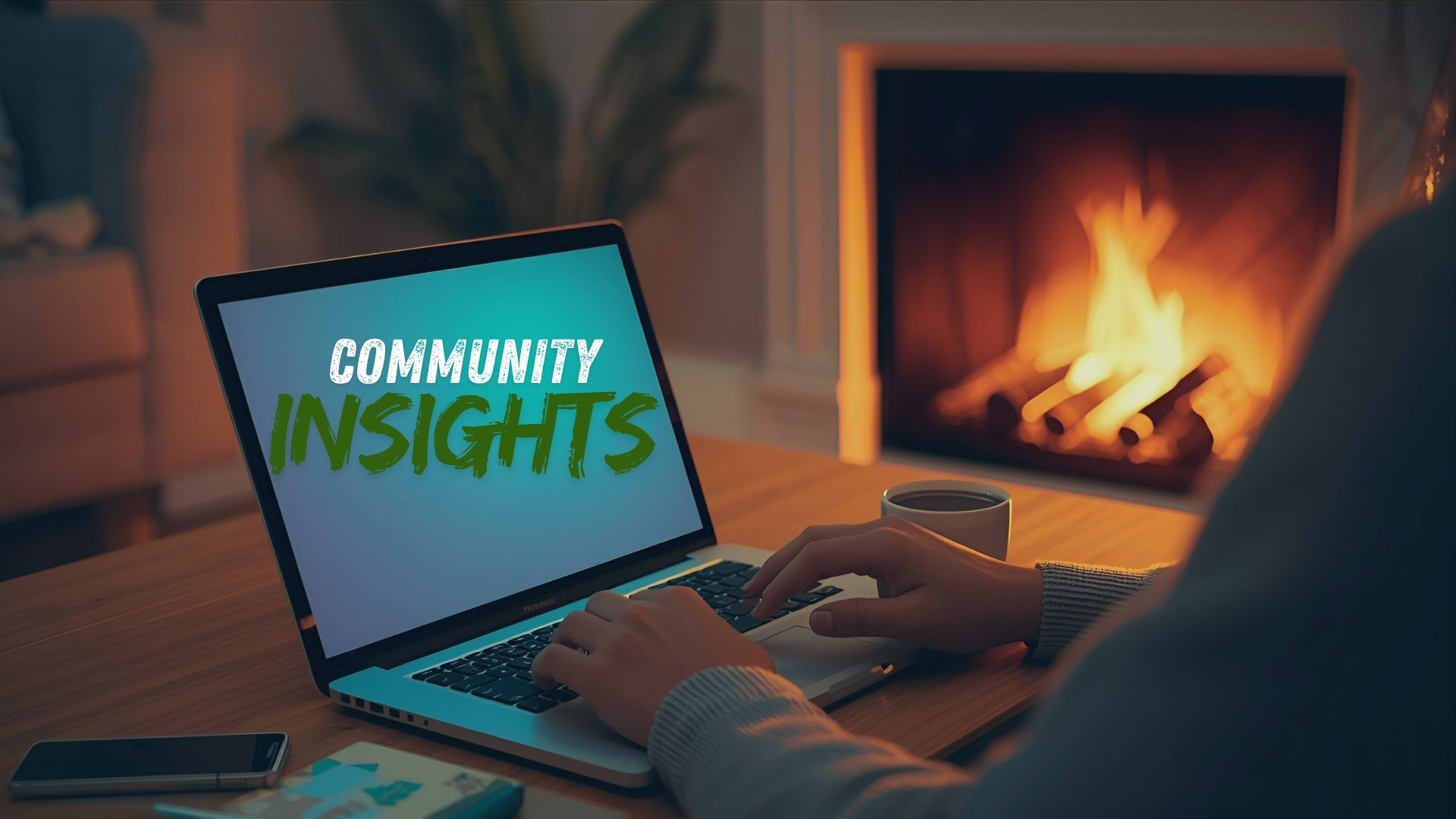 Person typing on a laptop that shows the words Community Insights, with a fireplace and coffee in the background, representing NorthSide GTA real estate insights.